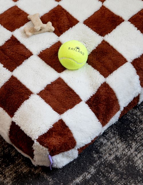 A brown-and-white checkered plush blanket with a lime tennis ball and small dog toy bone on top.