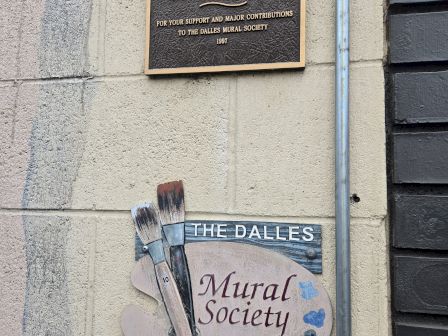 A wall plaque thanks Robert L. Keys for major contributions to the Dalles Mural Society (1997), beside a mural-art sign and brushes.