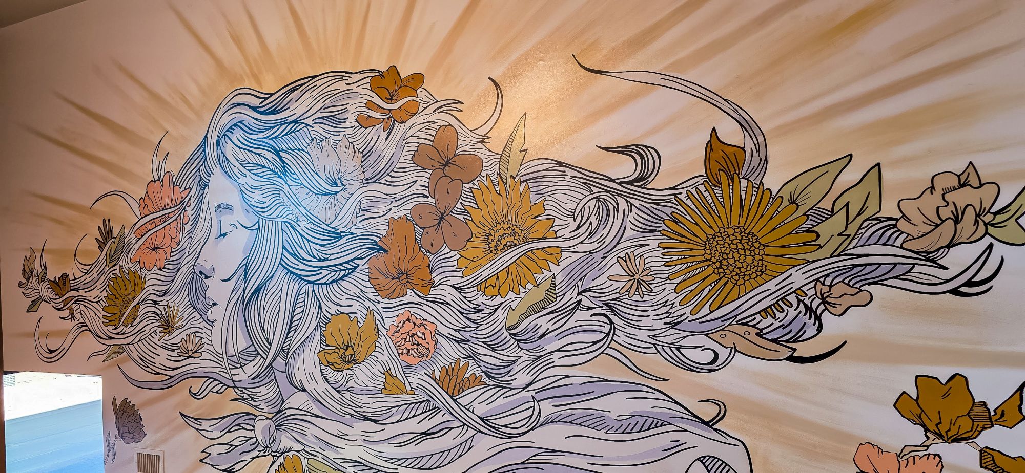Colorful mural with flowing lines and nature motifs. A wavy, white-haired figure intertwined with yellow, gold, pink floral elements and sunburst background.